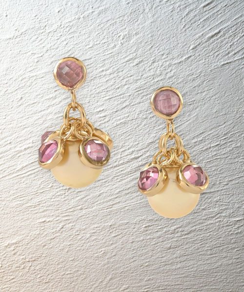 Gold and pink quartz earrings from the limited edition collection are displayed on a textured plaster background.